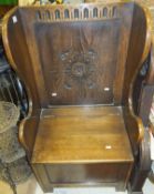 A 20th Century oak carved wing back box seated lambing style chair/settle