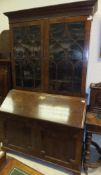 An early 19th Century mahogany bureau with blind fretwork to the cornice enclosing shelves,