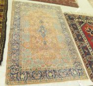A Persian rug, the central medallion in dark blue, pink, yellow and pale green on an apricot