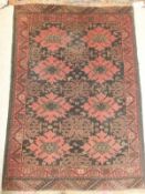 A Beluche type rug, the central brown ground with repeating red medallions, within a brown,