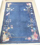 A Chinese rug in dark blue with vase and floral decoration to the border,