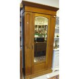 A walnut single mirror door wardrobe on plinth base