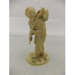 A Meiji period Japanese carved ivory okimono of an elderly gentleman carrying a stick and basket and