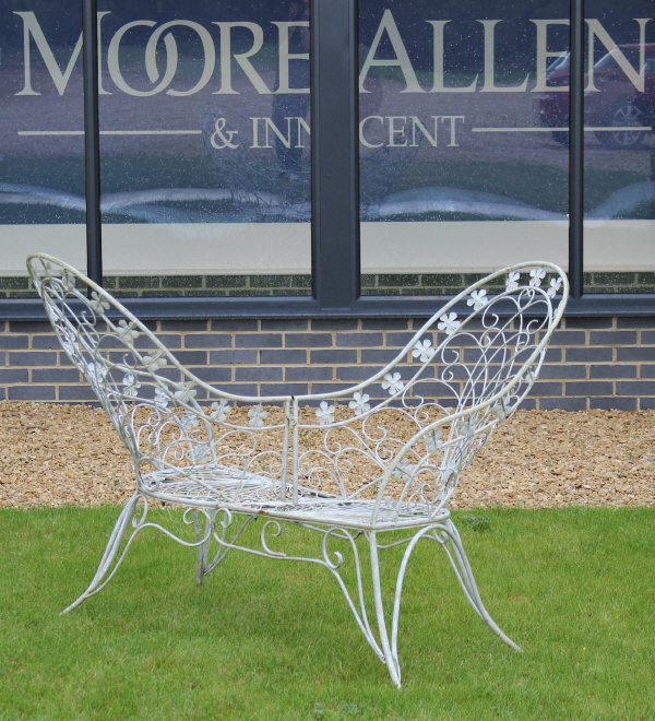 A painted iron and scrollwork decorated love seat