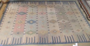 A Kelim style carpet, the pale ground with blue, pink, yellow, green and mushroom pattern,