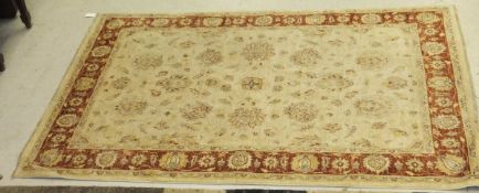 An Indian wool rug, the central panel with all over floral decoration on a cream ground,