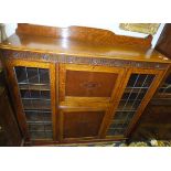 An oak secretaire cabinet with leaded glazed doors and writing compartment above single door