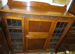 An oak secretaire cabinet with leaded glazed doors and writing compartment above single door