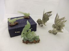 Three carved jade figures of birds on wooden stands,