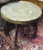 A circa 1900 Chinese padouk wood folding table on dragon mask feet with Benares type brass top