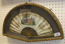 A framed French fan decorated with ladies in a landscape