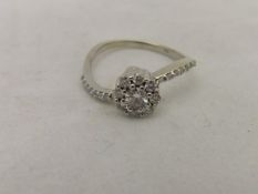 A 14ct white gold diamond set cluster ring with diamond chips to shoulders