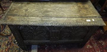 A 17th Century oak coffer, the top with later carved edge over a carved two panelled front,