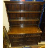 An oak dresser of three open shelves above two drawers and two cupboard doors below, on stile feet