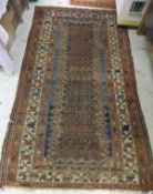 A Caucasian rug, the central panel with hook motifs on a green and blue ground, within a red,