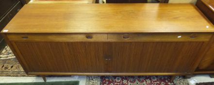 A Heal's teak sideboard with plain top above two drawers and tambour on turned feet, bears label