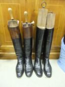A pair of brown and tan leather riding boots with wooden trees and turned handles, together with a