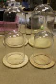 Four various glass domes on wooden bases