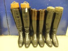 A pair of black leather riding boots with wooden trees, a pair of black rubber and brown leather