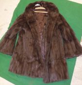 A dark brown three quarter length fur coat with satin lining,