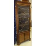 A circa 1900 mahogany free-standing corner cabinet with glazed door enclosing shelves over a