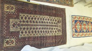 A Beluch prayer rug with central foliate decoration on a beige ground within a multiple plum ground