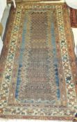 A Caucasian rug, the central panel with hook motifs on a green and blue ground, within a red,