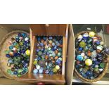 A box containing a collection of various vintage marbles,