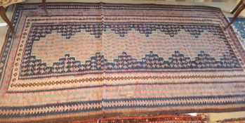 A Kelim rug in shades of salmon, cream, dark blue, duck egg blue and madder,