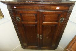 A Georgian oak two door hanging corner cupboard, the panelled doors with shell inlay decoration,
