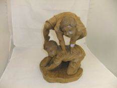 A carved wood figure group of two boys playing leap frog