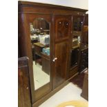A mahogany wardrobe with satinwood inlay, with two mirrored doors and central panelled door,