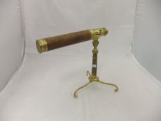 A modern brass and wooden telescope raised on a brass tripod stand