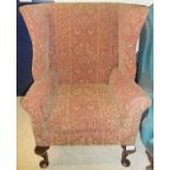 A circa 1900 upholstered wing back scroll arm chair on cabriole legs to pad feet