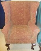 A circa 1900 upholstered wing back scroll arm chair on cabriole legs to pad feet