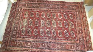 A Beluch rug with all-over elephant foot medallions on a burgundy ground within a stylised