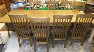 A modern oak extending dining table and eight matching comb back chairs with upholstered seats