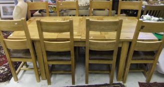 A rectangular oak extending dining table and set of eight matching bar back chairs with upholstered