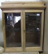 A waxed pine clerk's cabinet with sloping top above two glazed doors