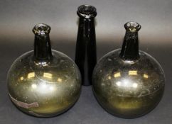 Two early green glass bulbous bodied wine bottles, together with a brown glass wine bottle of