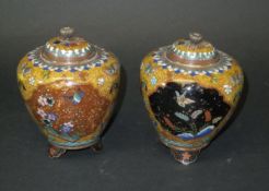 A pair of Chinese ovoid lidded pots on three footed bases with three panels to the body,