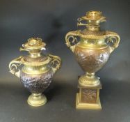A pair of elaborate embossed brass and copper oil lamp bases with serpentine handles,