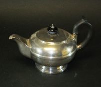 A George V silver teapot of squat form with reeded central band, raised on a circular foot (by H.