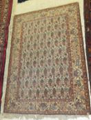 A Kashan rug, the central panel set with repeating hook motifs on a cream ground with stylised