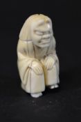 A 19th Century Japanese Meiji period carved ivory netsuke as a seated theatrical figure wearing a