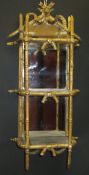 A 19th Century gilt and gesso framed three tier wall shelf with mirrored back, with swag and bow