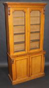 A Victorian oak bookcase cabinet, the moulded cornice above two glazed doors enclosing adjustable
