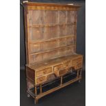 An 18th Century Welsh oak dresser, the boarded plate rack with stepped cornice above a set of cup