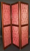 A Victorian mahogany framed three-fold vanity screen with plush pink self patterned upholstered