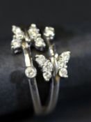 An 18 carat white gold split ring, each section decorated with a butterfly and single diamond,